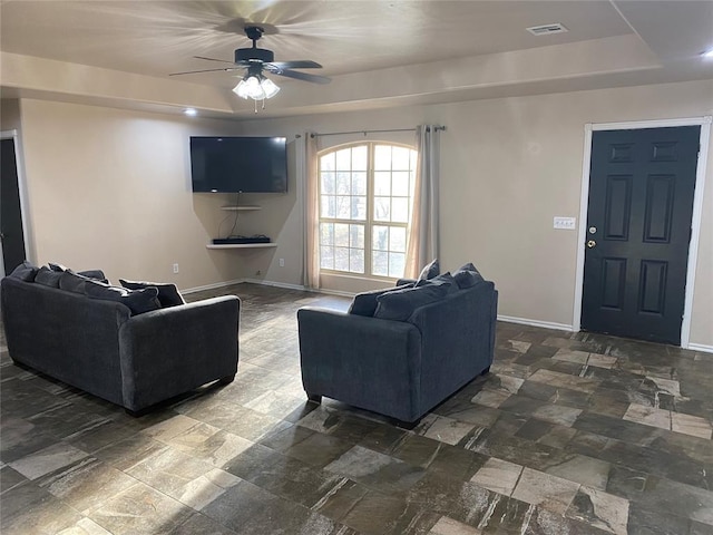 living room with a raised ceiling and ceiling fan