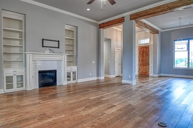 unfurnished living room with crown molding, built in shelves, a fireplace, and hardwood / wood-style flooring