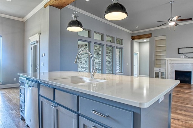 kitchen featuring sink, a center island with sink, light wood-type flooring, stainless steel dishwasher, and pendant lighting