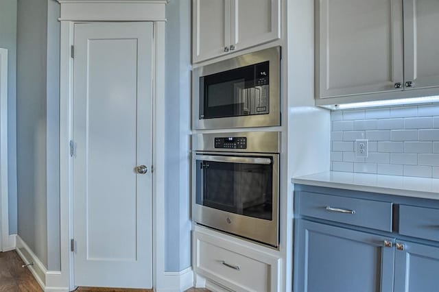 kitchen with tasteful backsplash, appliances with stainless steel finishes, and dark wood-type flooring