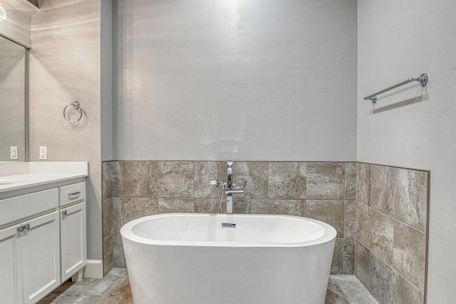 bathroom featuring vanity, a washtub, and tile walls