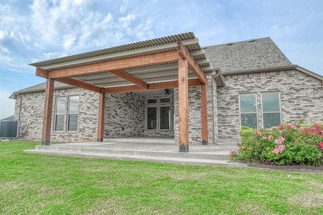 back of house with central AC unit, a lawn, and a patio area