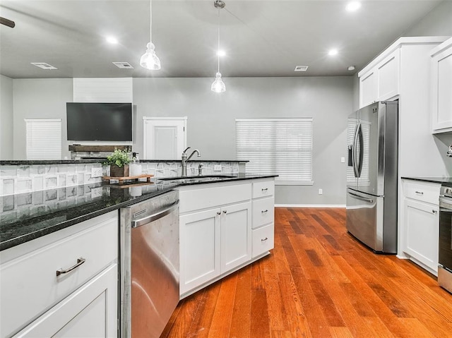 kitchen featuring sink, light hardwood / wood-style flooring, pendant lighting, stainless steel appliances, and white cabinets