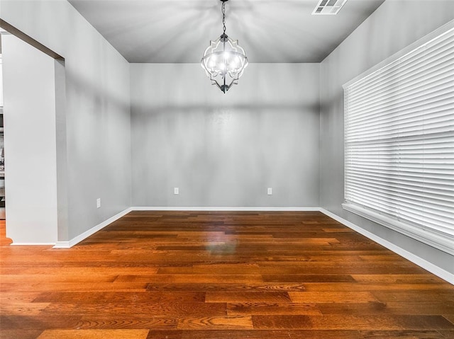 spare room with wood-type flooring and a chandelier