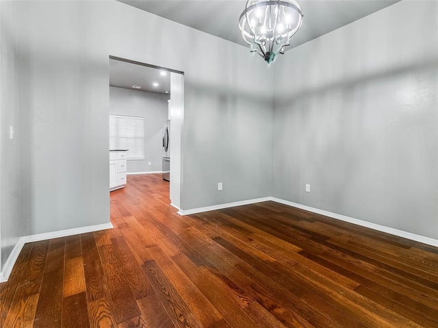 empty room with wood-type flooring and a chandelier