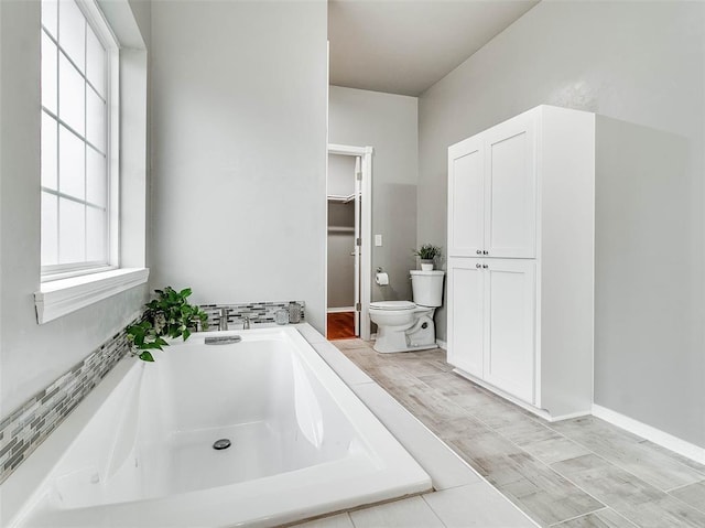 bathroom featuring a relaxing tiled tub and toilet