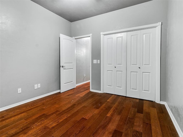 unfurnished bedroom with dark wood-type flooring and a closet