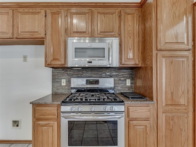 kitchen with dark stone countertops, stainless steel appliances, and backsplash