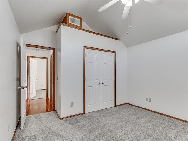 unfurnished bedroom with lofted ceiling, light carpet, a closet, and ceiling fan