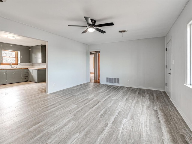 unfurnished living room with ceiling fan, light hardwood / wood-style floors, and sink