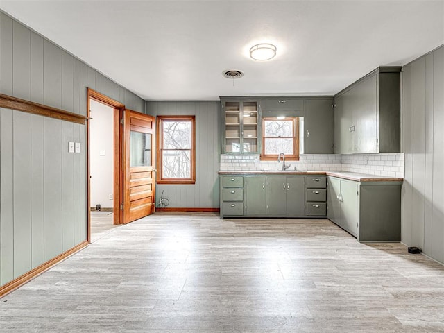 kitchen featuring plenty of natural light, sink, light hardwood / wood-style flooring, and backsplash