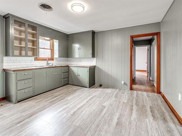 kitchen with tasteful backsplash, sink, and light hardwood / wood-style flooring