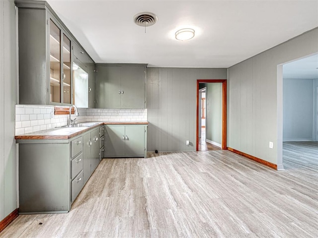 kitchen featuring gray cabinets, light hardwood / wood-style floors, sink, and backsplash