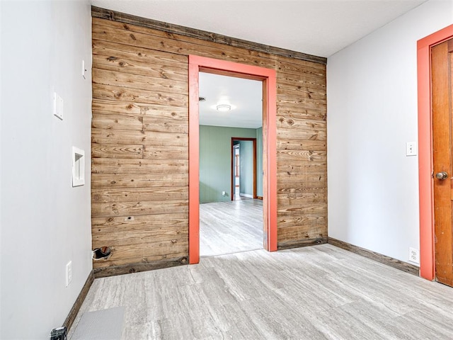 empty room featuring wooden walls and light hardwood / wood-style floors