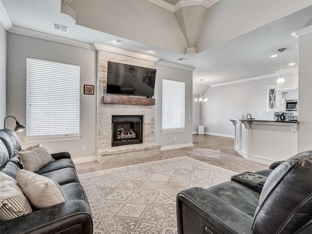 carpeted living room featuring ornamental molding, a stone fireplace, and a notable chandelier