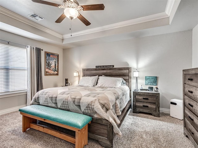 carpeted bedroom with crown molding, a tray ceiling, and ceiling fan