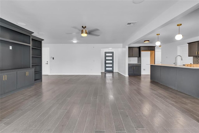 unfurnished living room with ceiling fan, dark hardwood / wood-style floors, and sink