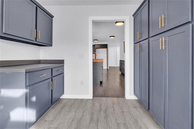 kitchen with gray cabinetry and light hardwood / wood-style flooring