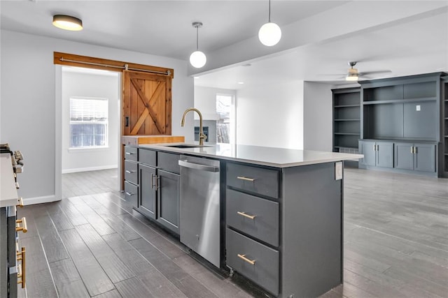 kitchen featuring pendant lighting, dishwasher, an island with sink, sink, and a barn door