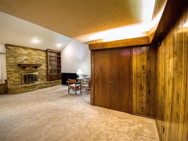 interior space with a fireplace, wooden walls, a textured ceiling, and carpet flooring