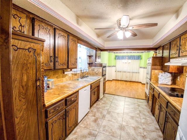 kitchen with light tile patterned flooring, sink, ceiling fan, a raised ceiling, and white appliances