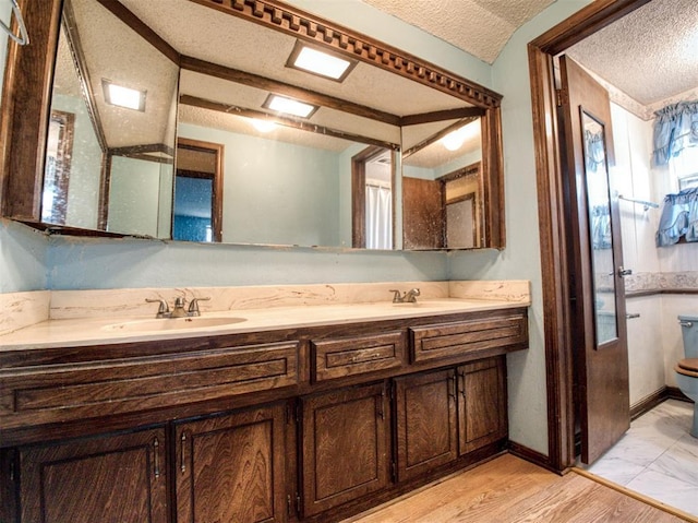 bathroom with vanity, toilet, and a textured ceiling