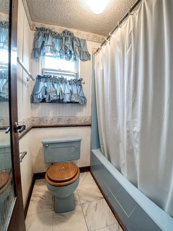 bathroom with shower / tub combo with curtain, a textured ceiling, and toilet