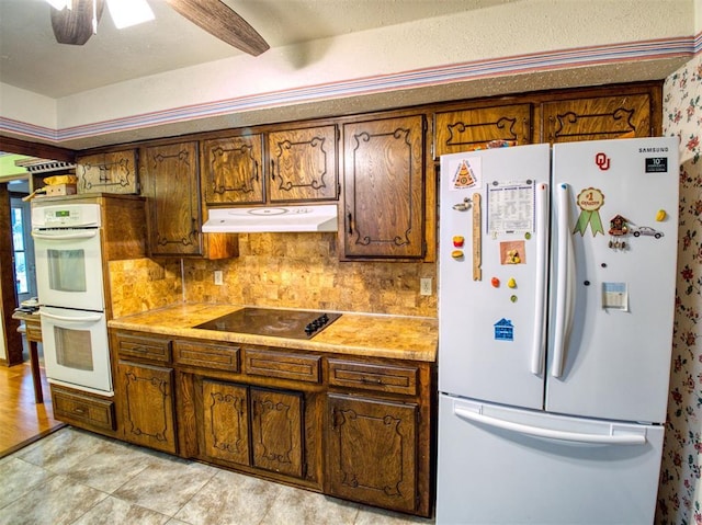 7318 Hummingbird Cir, Oklahoma City, OK 73162 - kitchen featuring white appliances, under cabinet range hood, decorative backsplash, brown cabinetry, and light countertops