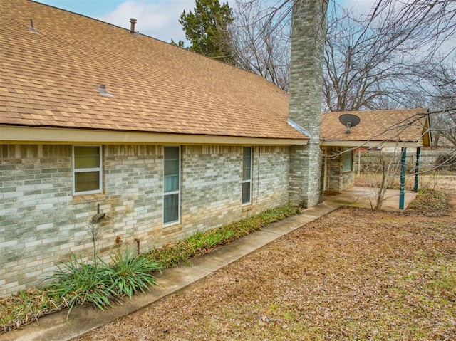 7318 Hummingbird Cir, Oklahoma City, OK 73162 - view of home's exterior with a chimney, a patio area, and roof with shingles