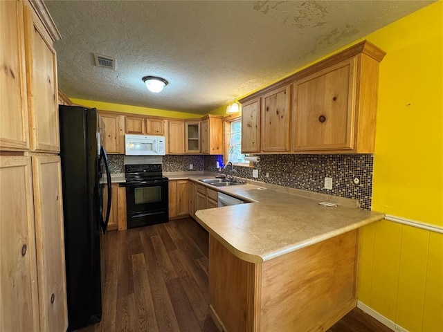 kitchen featuring dark hardwood / wood-style floors, black appliances, sink, decorative backsplash, and kitchen peninsula