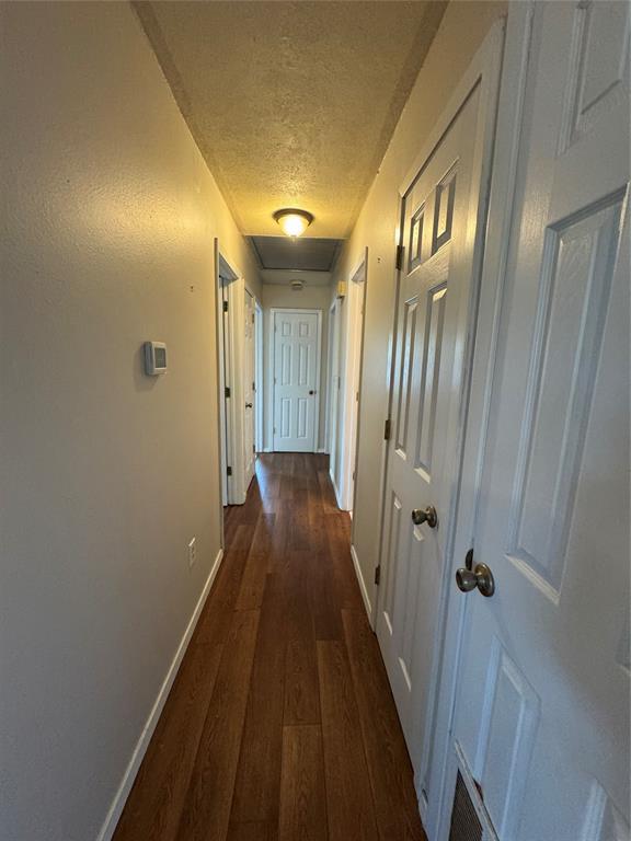 hallway with dark hardwood / wood-style floors and a textured ceiling