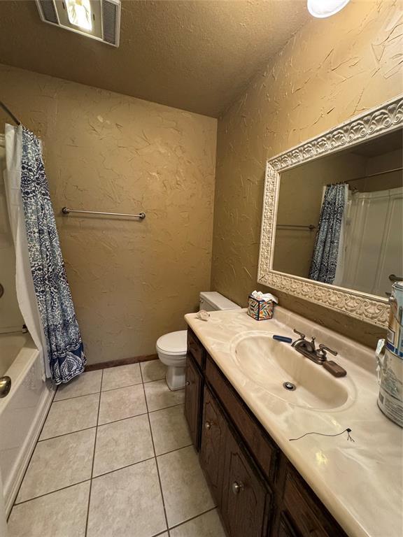 full bathroom featuring vanity, toilet, shower / bath combo, tile patterned floors, and a textured ceiling