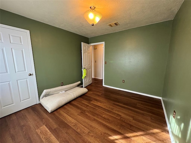 unfurnished bedroom with dark hardwood / wood-style floors and a textured ceiling