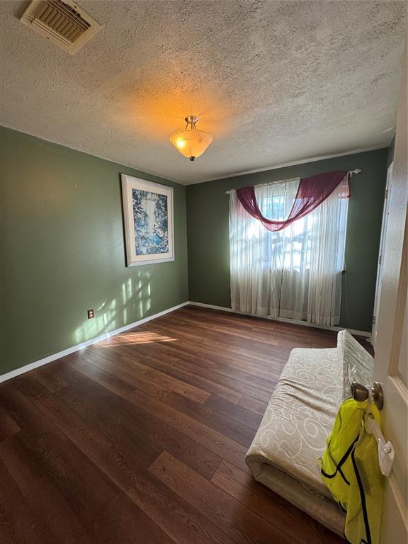 spare room featuring hardwood / wood-style floors and a textured ceiling