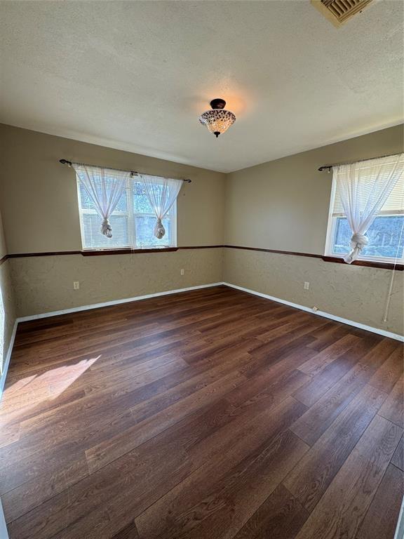 spare room with dark hardwood / wood-style floors and a textured ceiling