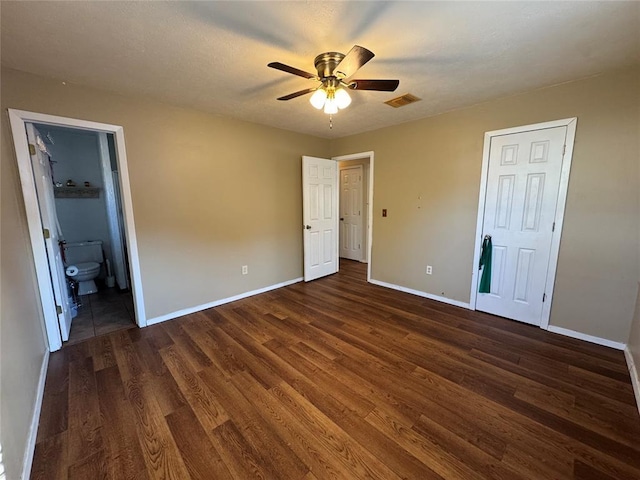 unfurnished bedroom with ensuite bath, dark hardwood / wood-style floors, and ceiling fan