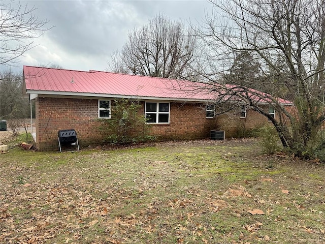 rear view of property with central AC unit and a lawn