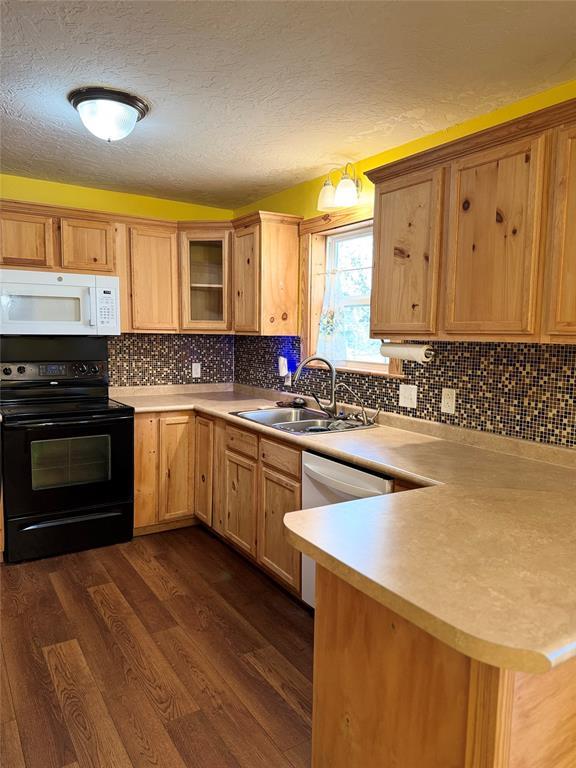 kitchen featuring black range with electric stovetop, backsplash, sink, dark hardwood / wood-style floors, and kitchen peninsula