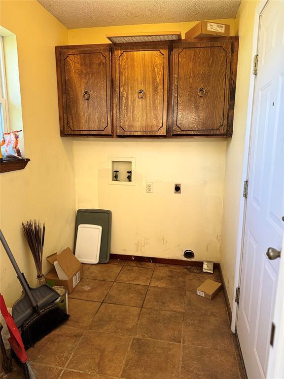 clothes washing area with cabinets, electric dryer hookup, a textured ceiling, and hookup for a washing machine