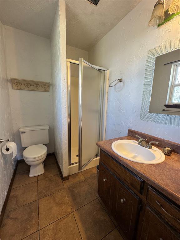 bathroom featuring vanity, a shower with shower door, and a textured ceiling