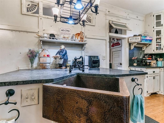 506 S Evans Ave, El Reno, OK 73036 - kitchen featuring hardwood / wood-style floors, white cabinets, decorative backsplash, hanging light fixtures, and ornamental molding