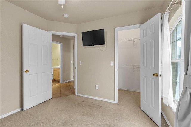 unfurnished bedroom featuring a spacious closet, light colored carpet, and a closet