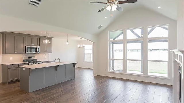 kitchen featuring appliances with stainless steel finishes, decorative light fixtures, a kitchen island with sink, and gray cabinetry