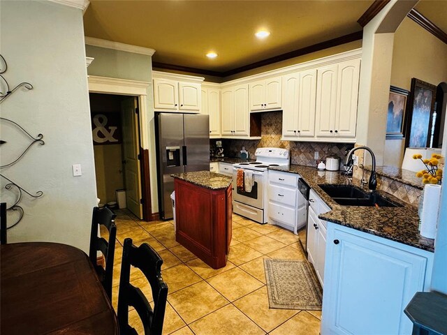 kitchen featuring sink, appliances with stainless steel finishes, white cabinetry, dark stone countertops, and decorative backsplash