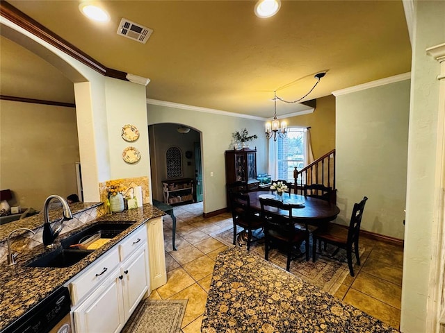 kitchen with sink, hanging light fixtures, dishwasher, dark stone counters, and white cabinets