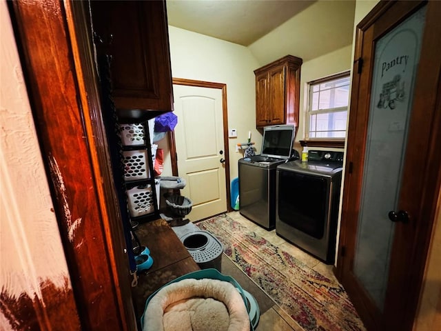 laundry area featuring cabinets, washing machine and clothes dryer, and tile patterned floors