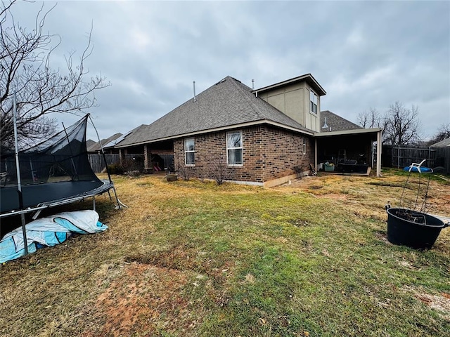 view of side of property featuring a trampoline and a lawn