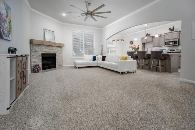 living room with a fireplace, sink, light colored carpet, ceiling fan, and crown molding