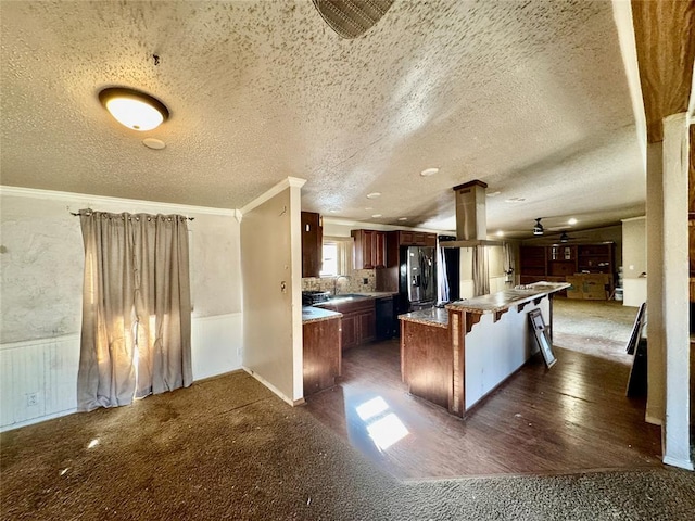 kitchen with ornate columns, a breakfast bar area, a center island, stainless steel fridge with ice dispenser, and crown molding