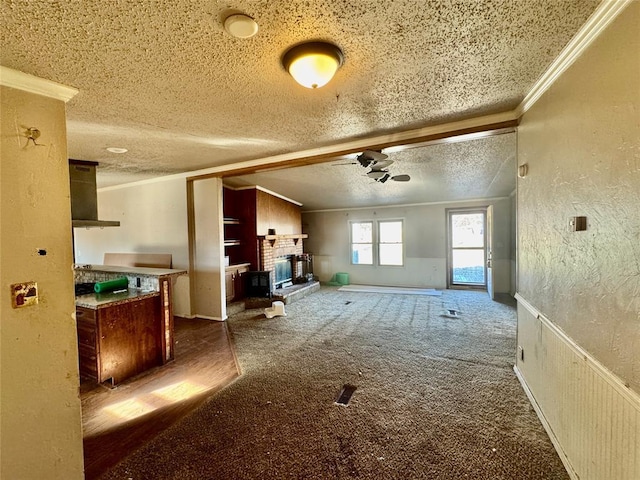 miscellaneous room featuring a fireplace, ornamental molding, a textured ceiling, and dark colored carpet